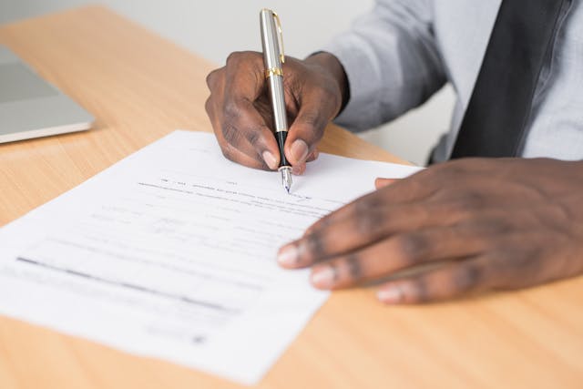 Mãos de pessoa preta assinando um contrato